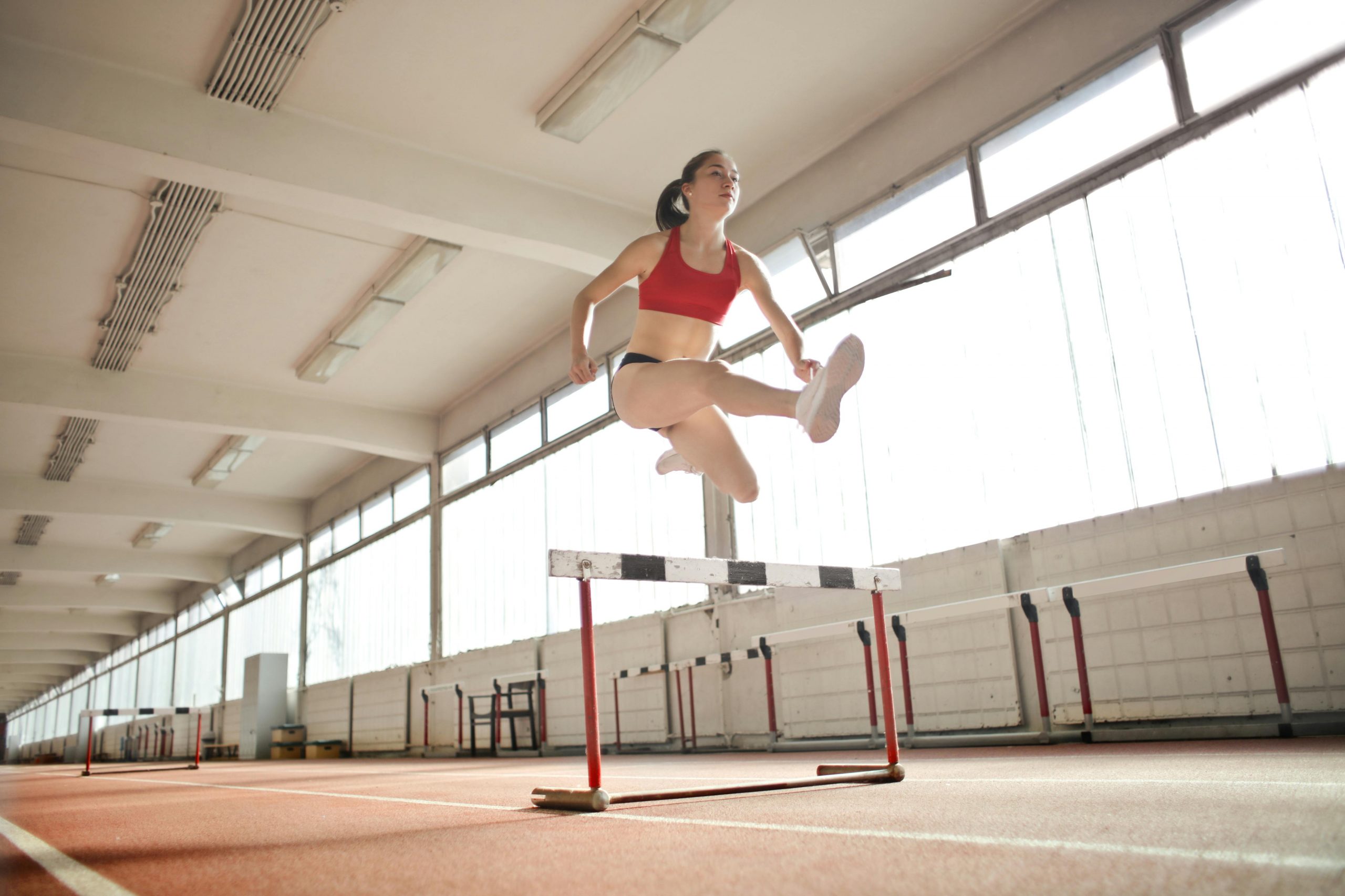 Dynamic action shot of a woman hurdling indoors, showcasing strength and agility.